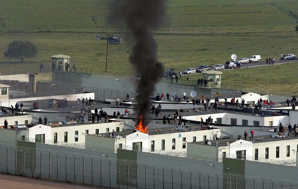 MALANDRINO, GREECE: Protesting inmates at a Greek high-security prison in Malandrino, central Greece light fires on the roof of the prison 25 April 2007. Squads of riot police went into the prison and gained control of most of the complex though 100 inmates remained on a roof top for a third day.Trouble in Greece's prison system spread throughout the country after a young inmate in Malandrino, linked to an Athens bank robbery shootout in 2006, was allegedly beaten by guards on Monday. AFP PHOTO/Dimitris Dimitriou (Photo credit should read DIMITRIS DIMITRIOU/AFP/Getty Images)
